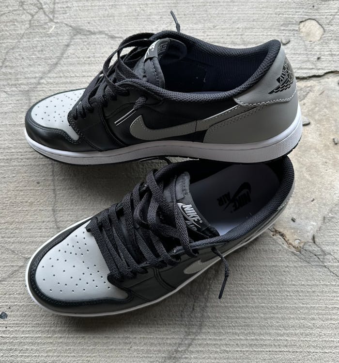 services-01 High-angle view of black and gray sneakers with Nike logo on a textured concrete background.